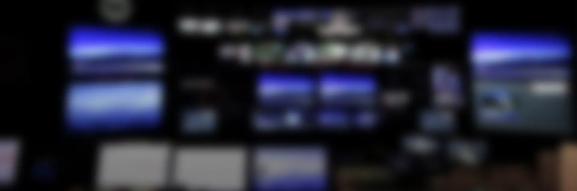 Blurry, background image of a television newsroom.