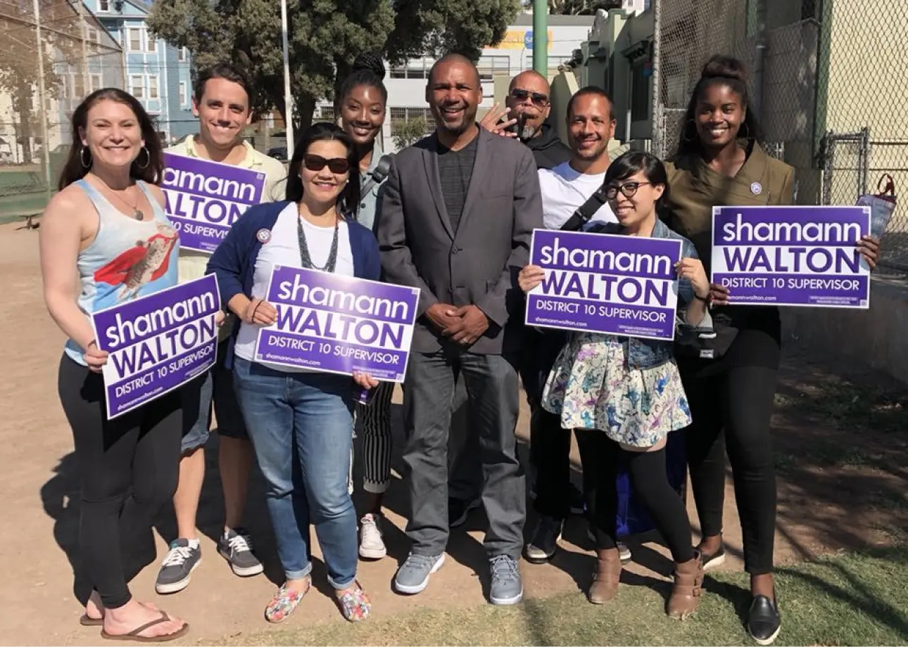 Candidate Shamann Walton poses with eight multi-racial supporters, holding signs